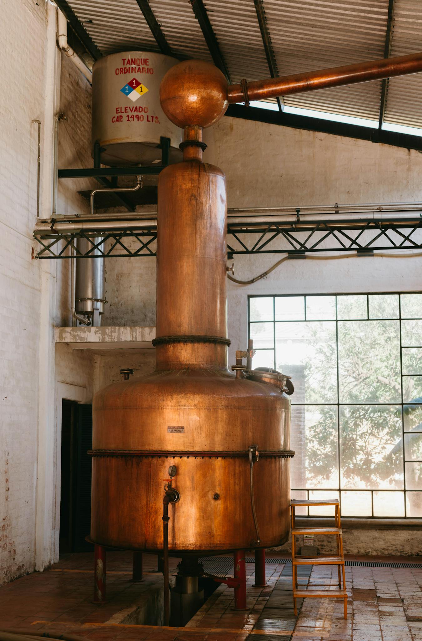 Copper distillation tank in an industrial facility with natural lighting.